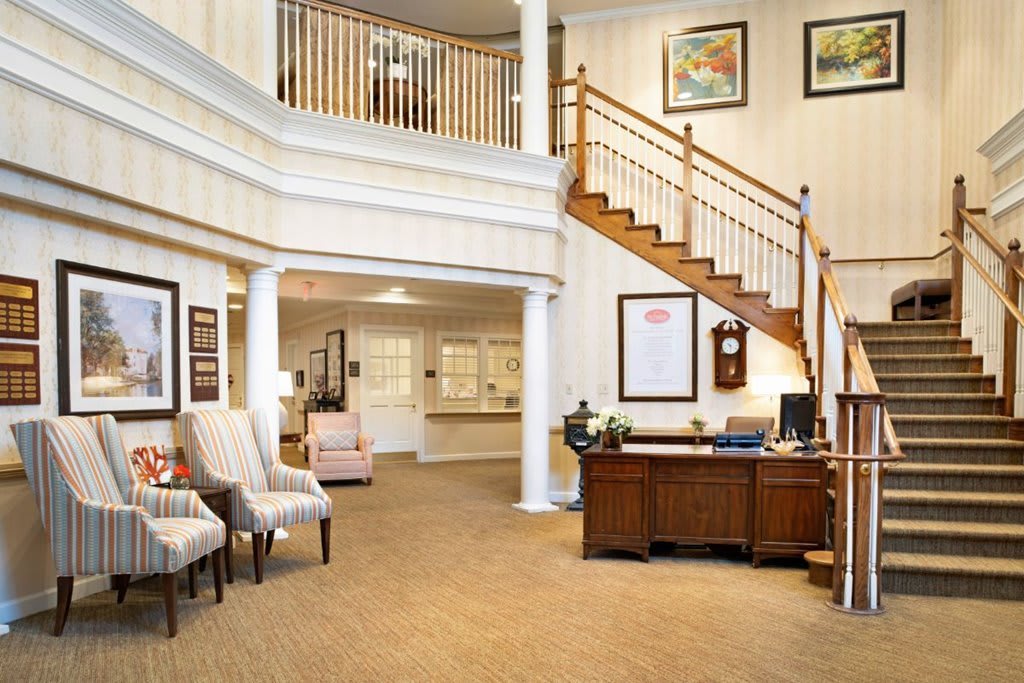 A welcoming lobby area with a wooden staircase, a desk, and seating arrangements.