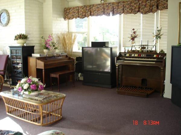 A cozy living room featuring a piano, organ, and a large television.