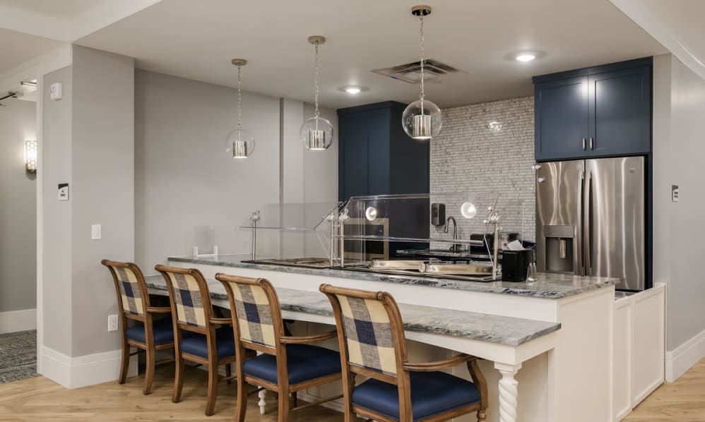A modern kitchen featuring a marble countertop with bar stools and stylish pendant lighting.