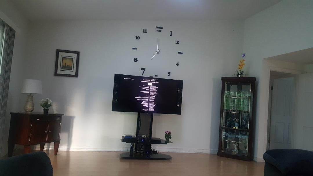 A living room setup featuring a large TV and modern wall clock.