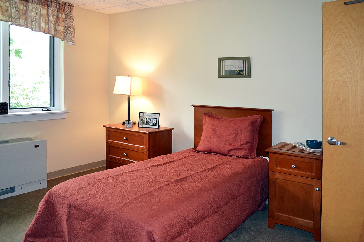 A cozy bedroom with a single bed, wooden nightstands, and a lamp.