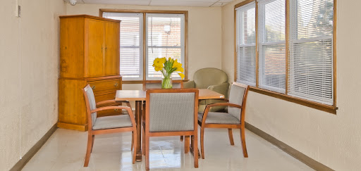 A cozy dining area featuring a wooden table, chairs, and a vibrant bouquet of flowers.