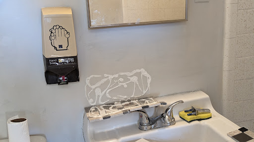 A bathroom sink area featuring a mirror, soap dispenser, and hand washing instructions.