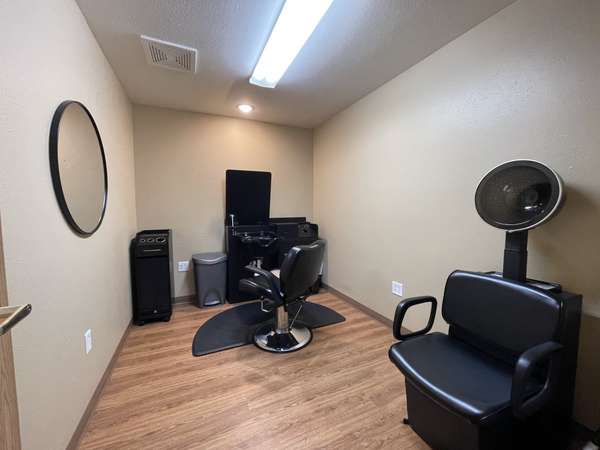 An empty hair salon room with a barber chair and mirror.