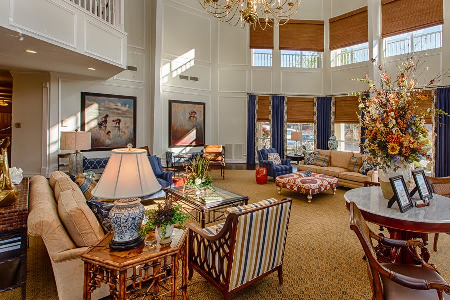 A spacious and elegantly decorated living room with ample seating, large windows, and a chandelier.