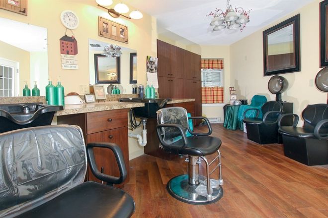 A cozy hair salon interior with stylish chairs, mirrors, and warm lighting.
