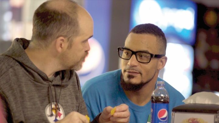 Two individuals engaged in a conversation over snacks and Pepsi.