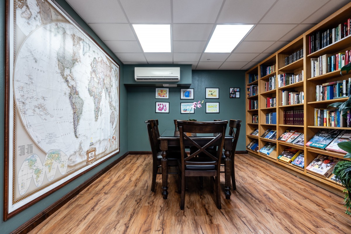 A cozy library study room with a large world map and wooden furniture.