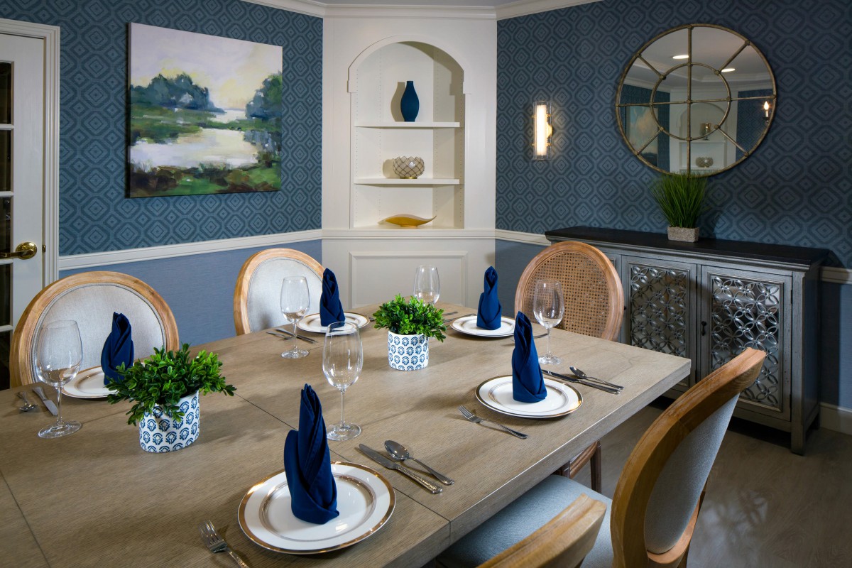 Elegant dining room with a stylish table setting, featuring blue napkins and decorative plants.