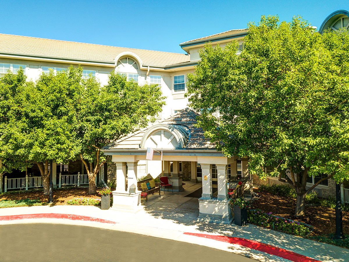 A sunny day at the entrance of a building surrounded by trees.