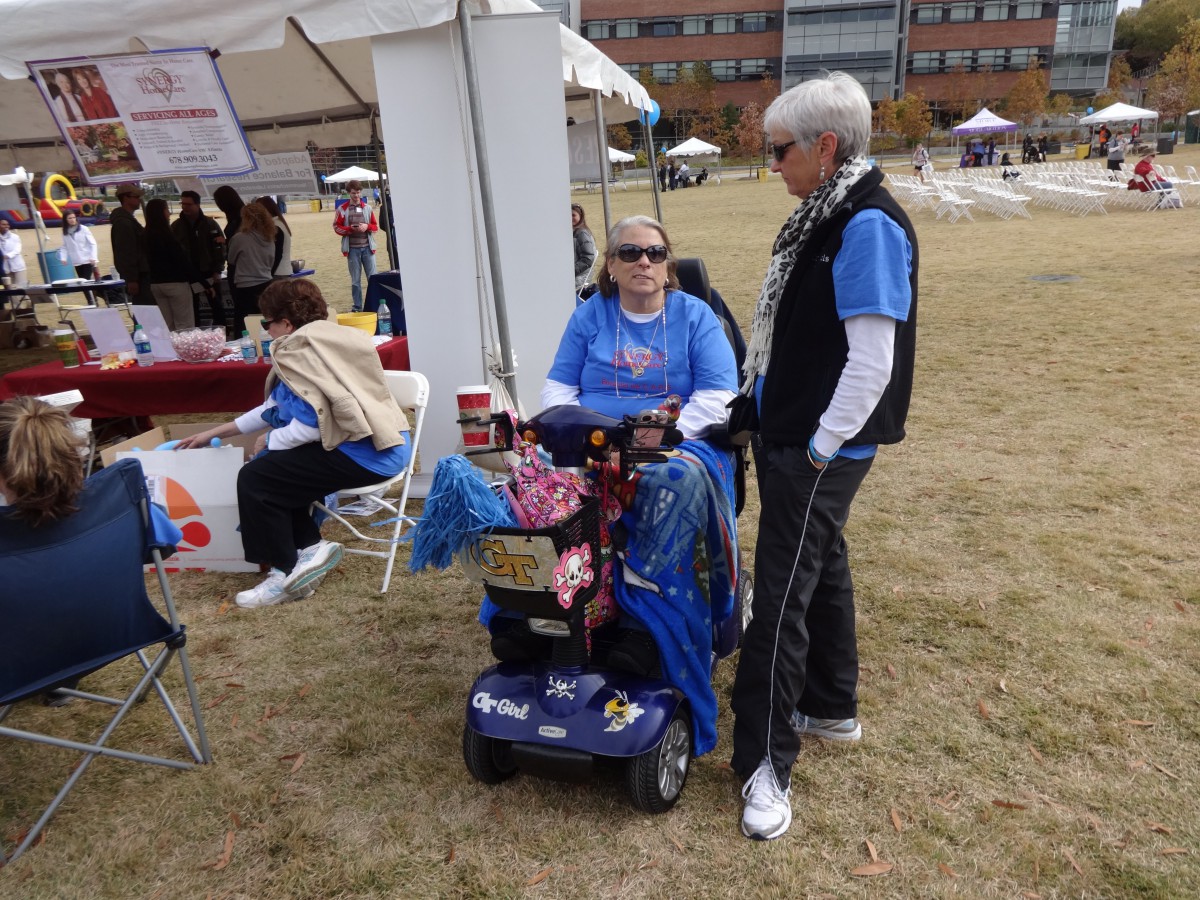 A group of people interacting at an outdoor event, with one person seated in a wheelchair.