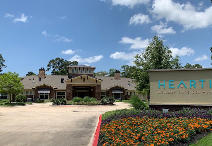 A building with a sign and landscaped driveway under a partly cloudy sky.