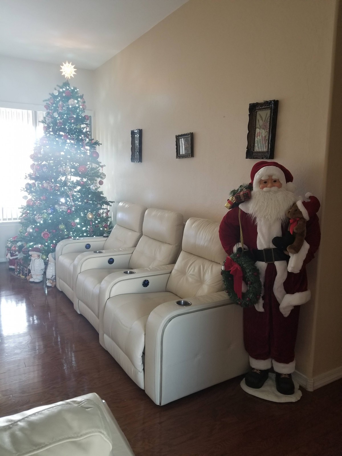 A living room decorated for Christmas with a tree and Santa Claus figure beside the couch.