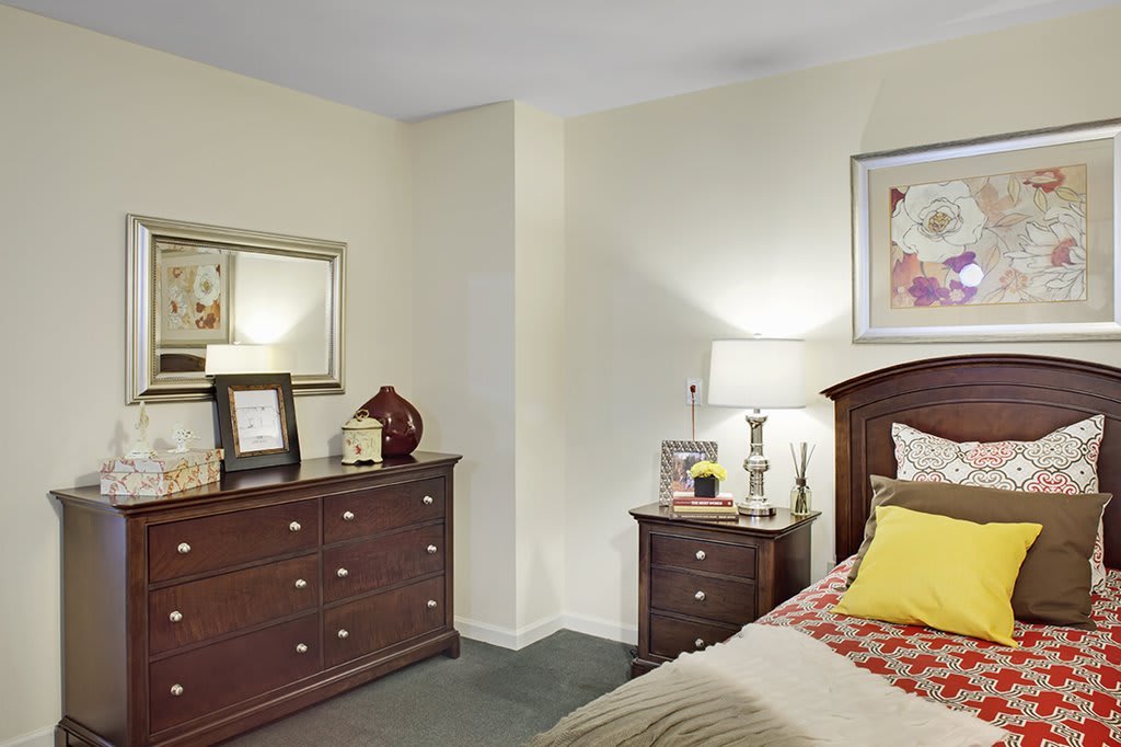 A cozy bedroom featuring a dresser, nightstand, and decorative accents.