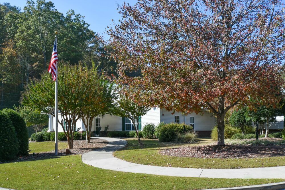 A scenic view of a building surrounded by trees with an American flag and a curved pathway.
