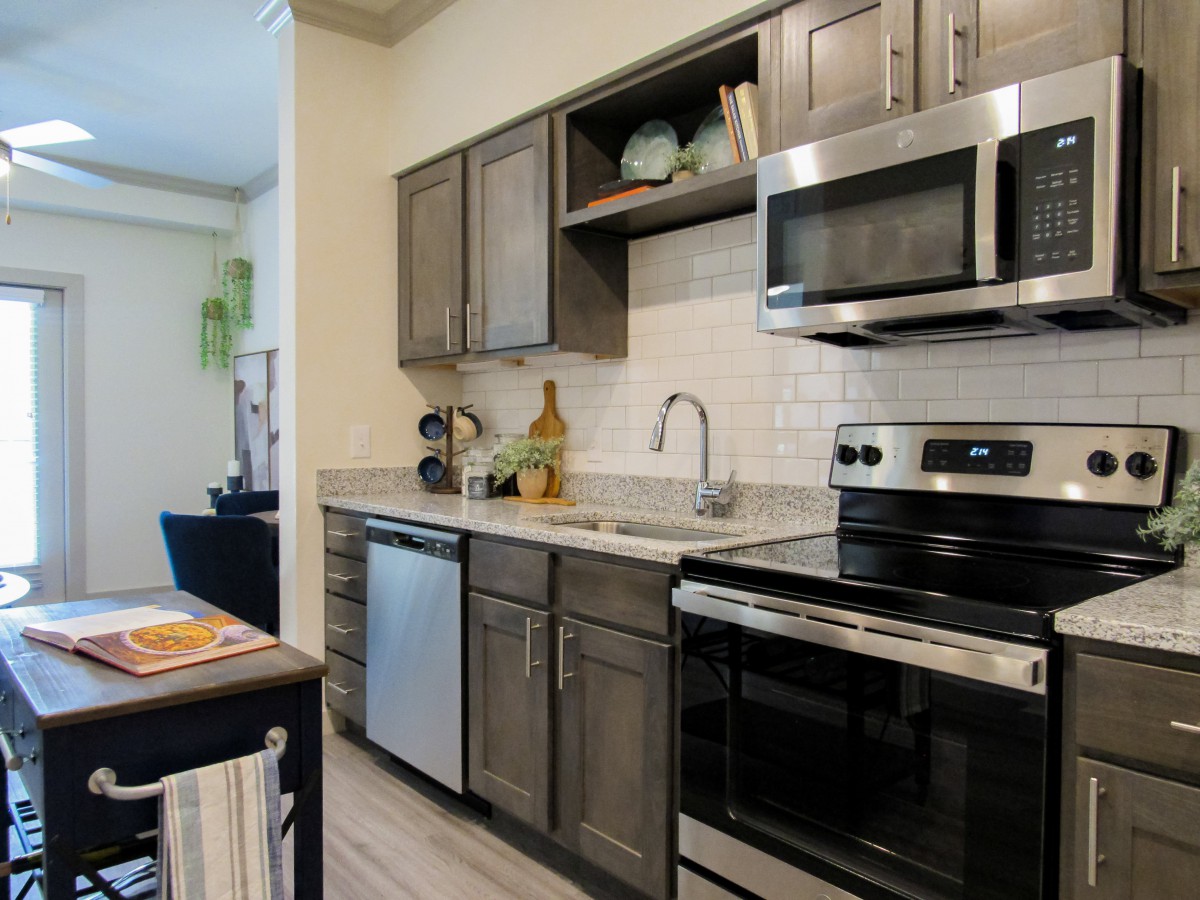 A modern kitchen with stainless steel appliances and dark wooden cabinets.