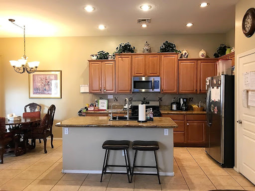 A modern kitchen featuring wooden cabinets, a spacious countertop, and bar stools for casual dining.