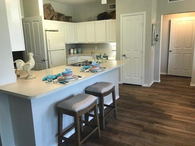 A modern kitchen with a countertop dining area and white cabinets.
