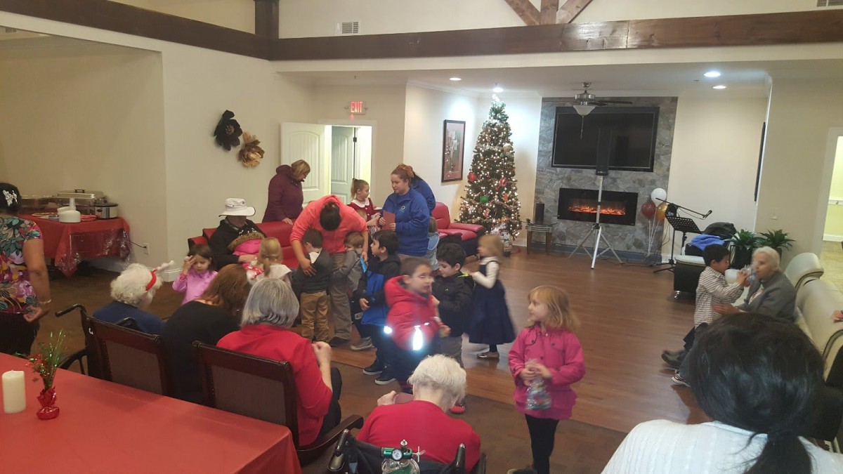 A festive gathering with children and adults celebrating around a Christmas tree indoors.