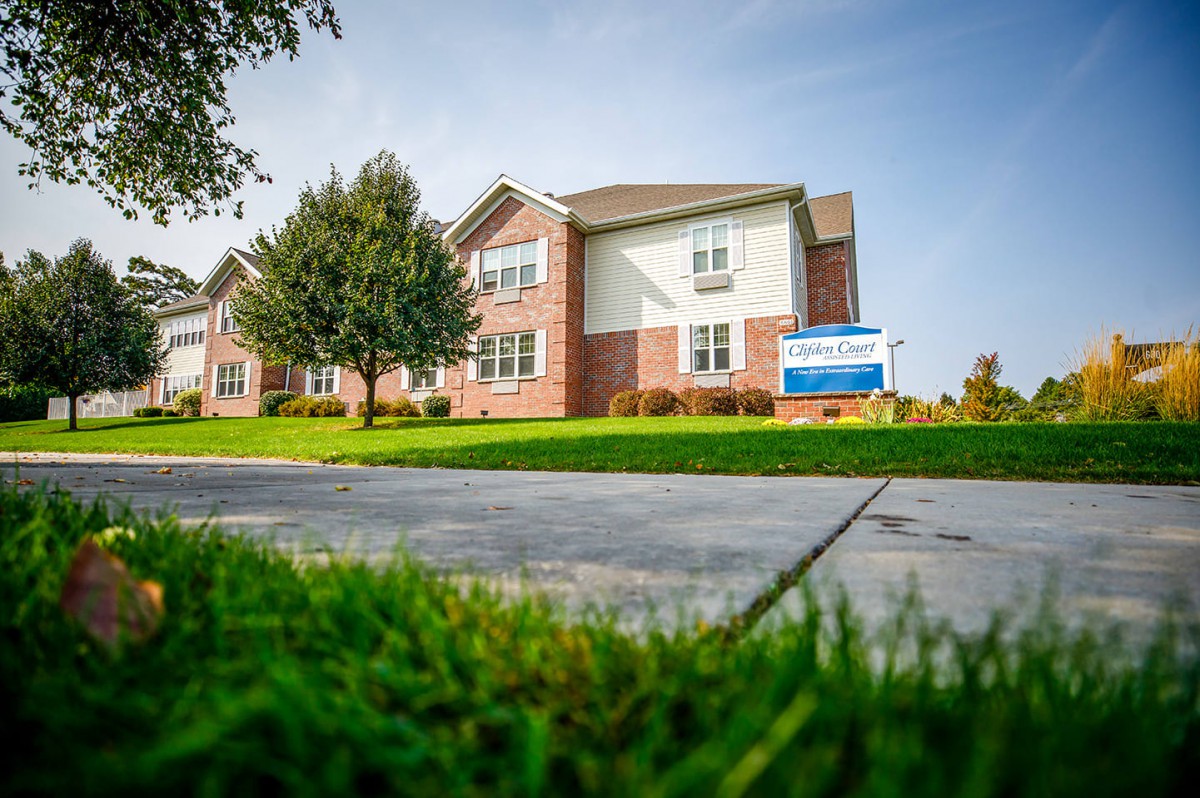 A residential apartment building with a well-maintained lawn and sidewalk.