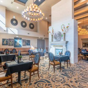 An elegant restaurant interior featuring chandeliers and a cozy fireplace.