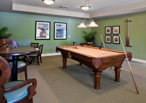 A spacious recreation room featuring a classic pool table, set against stylish green walls and elegant decor.