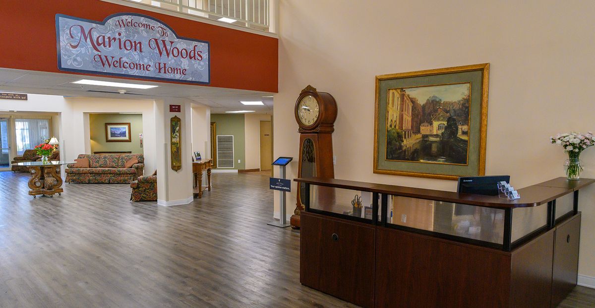 A spacious lobby area with a large clock, a painting, and wooden flooring.