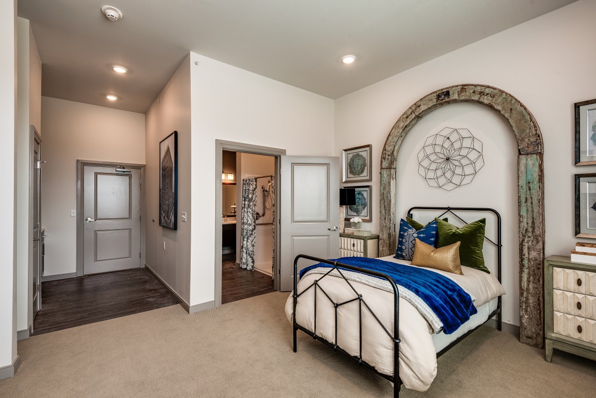 A modern bedroom with elegant decor, featuring a metal frame bed and stylish wall art.