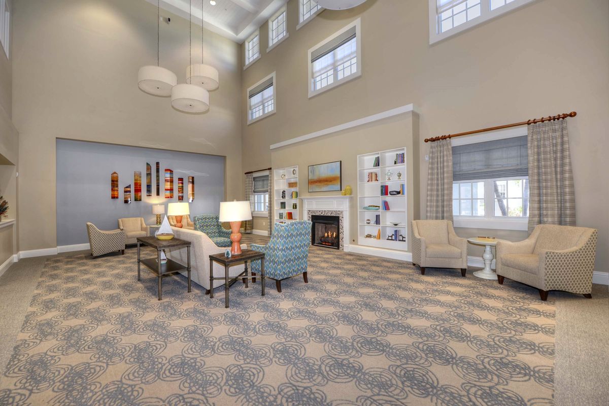 A spacious and elegantly designed living room with high ceilings, featuring comfortable seating and a cozy fireplace.