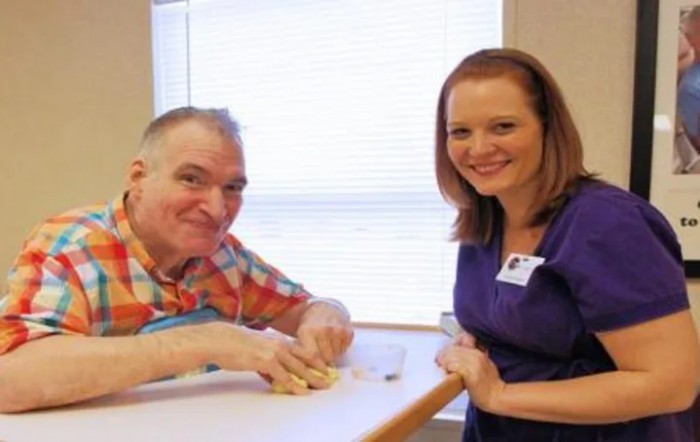 A man and a woman smiling while interacting at a table indoors.