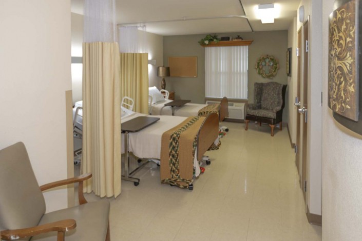 A hospital room with multiple beds and privacy curtains.