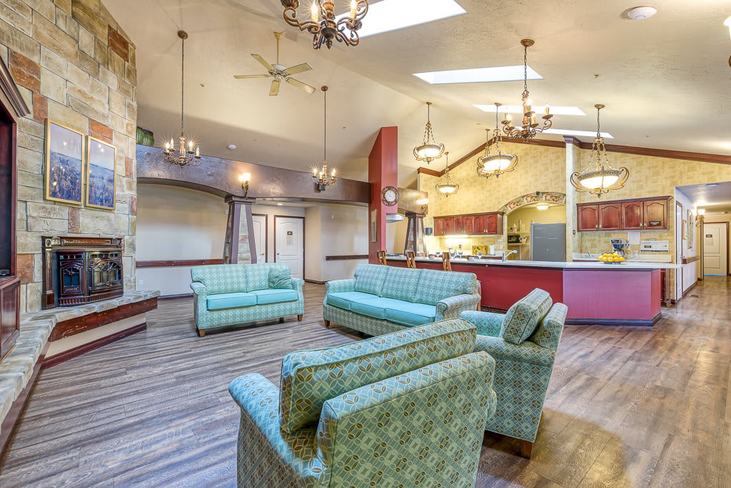 A spacious and modern living room with cozy sofas, chandeliers, and a wooden floor.