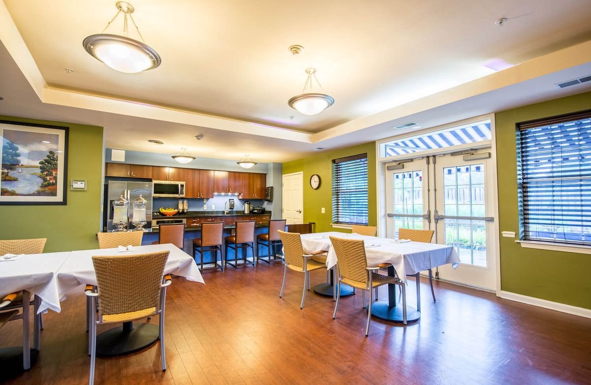 A modern dining area with an open kitchen, featuring wooden flooring and contemporary furniture.