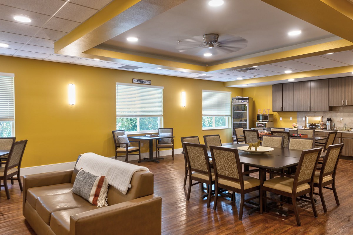 A cozy living space featuring a combined dining and kitchen area with yellow walls and wooden flooring.