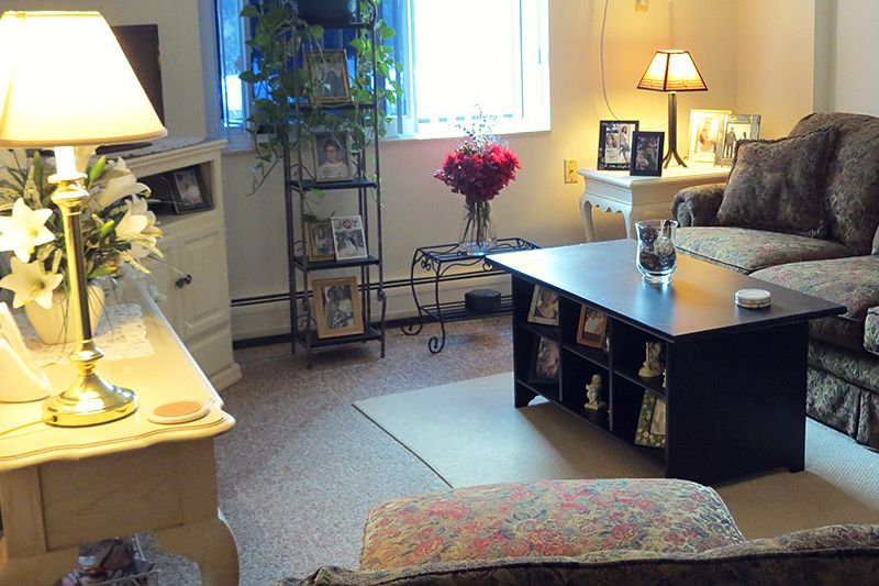 A cozy living room with warm lighting, featuring a coffee table, decorative lamps, and framed pictures.