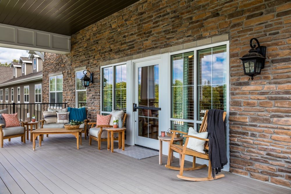 A welcoming porch with rocking chairs and cozy pillows against a stone wall backdrop.