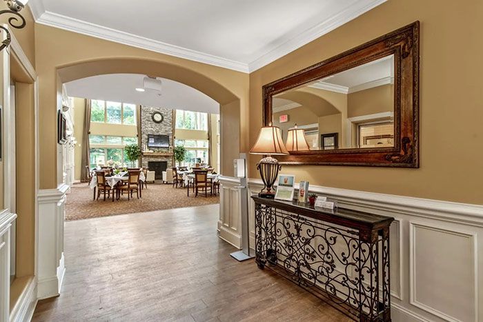 A welcoming lobby area featuring elegant decor, a large mirror, wooden flooring, and warm lighting.