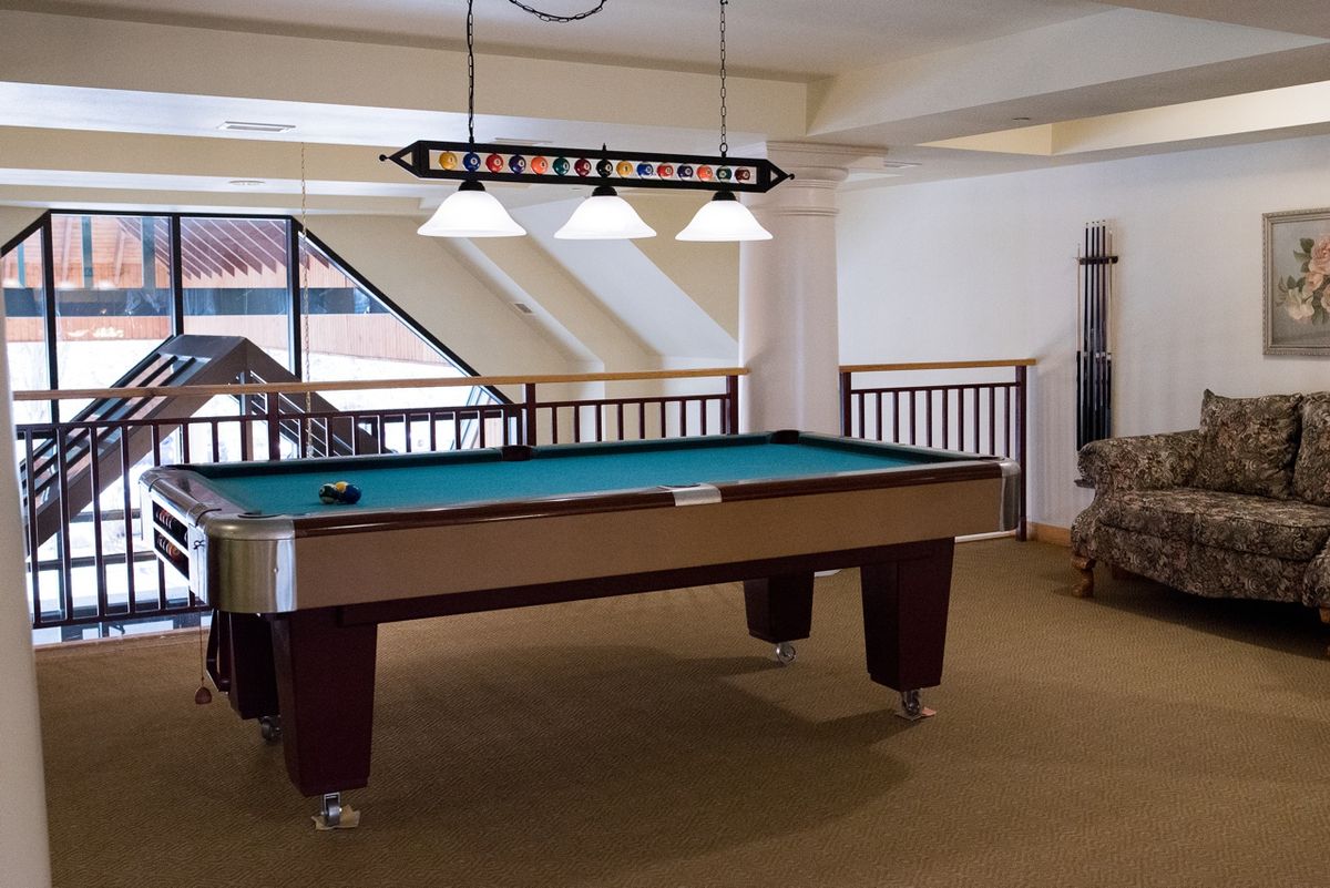 A well-lit game room featuring a billiards table.