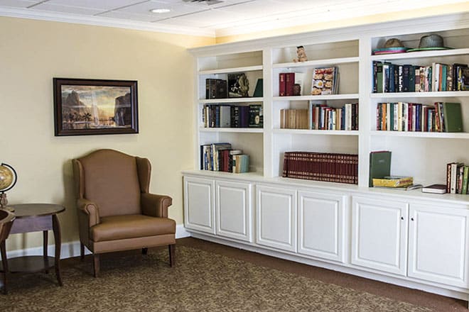 A cozy reading nook with a large bookshelf and an armchair.