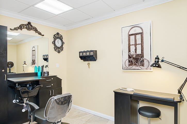 A well-decorated salon interior featuring styling chairs, a mirror, and elegant wall art.
