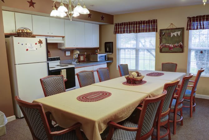 A cozy kitchen and dining area with a large table, surrounded by chairs, and adorned with warm decorations.
