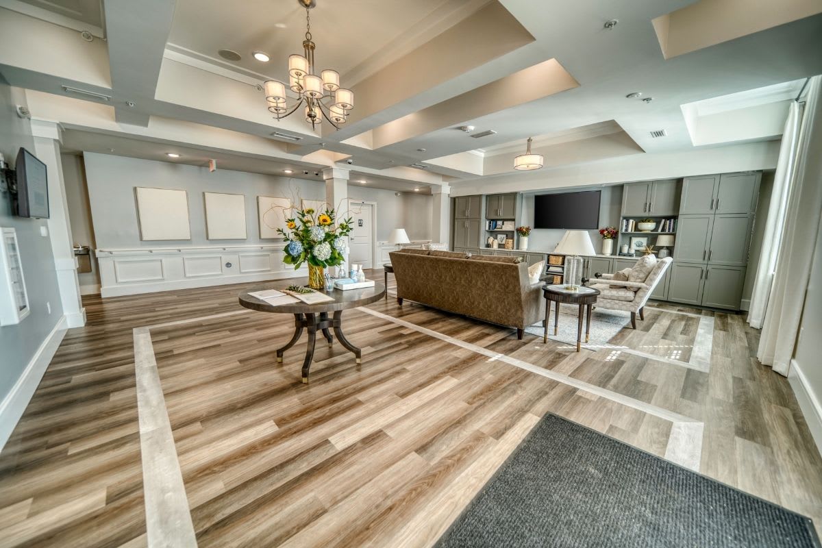 A spacious and elegantly designed living room with modern furnishings, a chandelier, and hardwood flooring.
