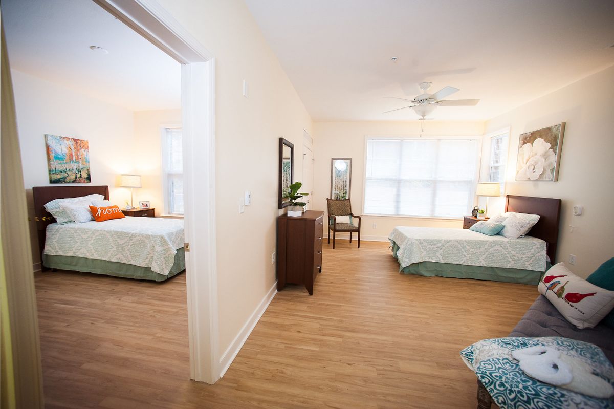 A spacious and bright bedroom with two beds, featuring a hardwood floor and ample natural light.