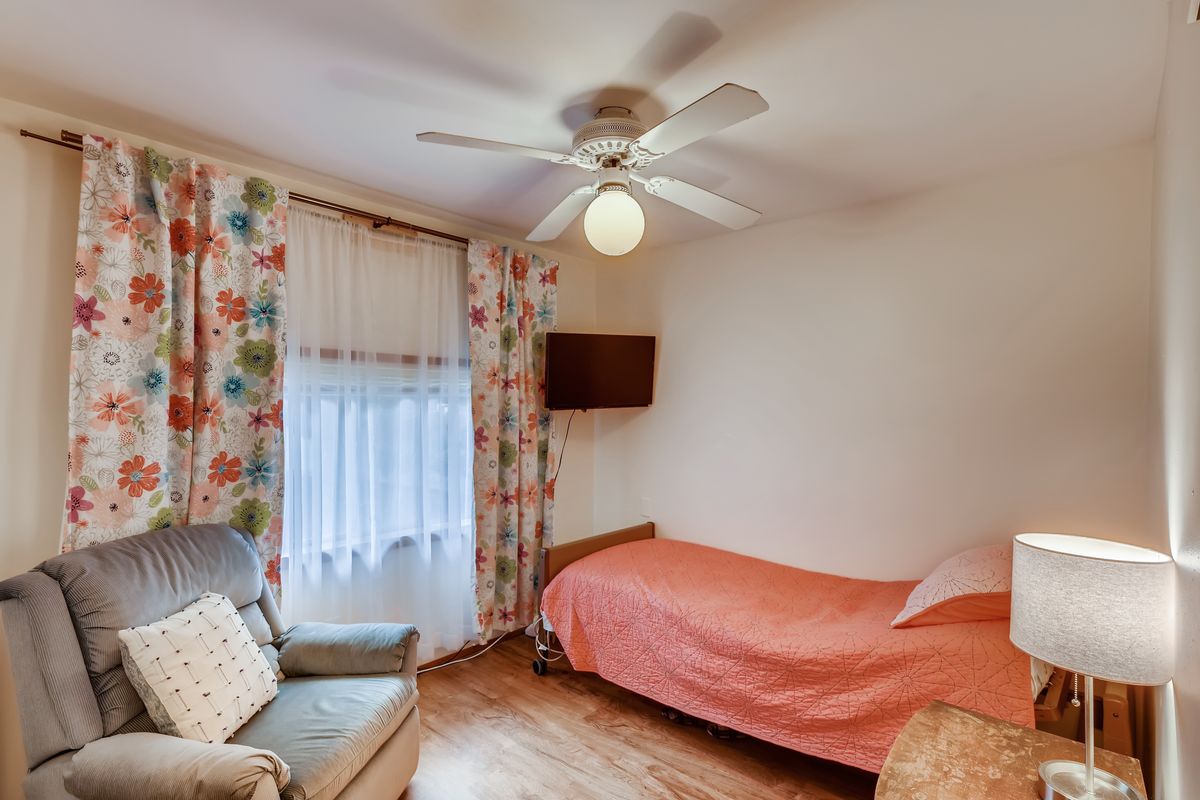 A cozy bedroom with a single bed, floral curtains, and a ceiling fan.