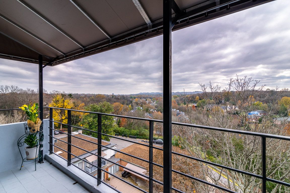 A scenic view from a balcony overlooking a lush landscape with a cloudy sky.