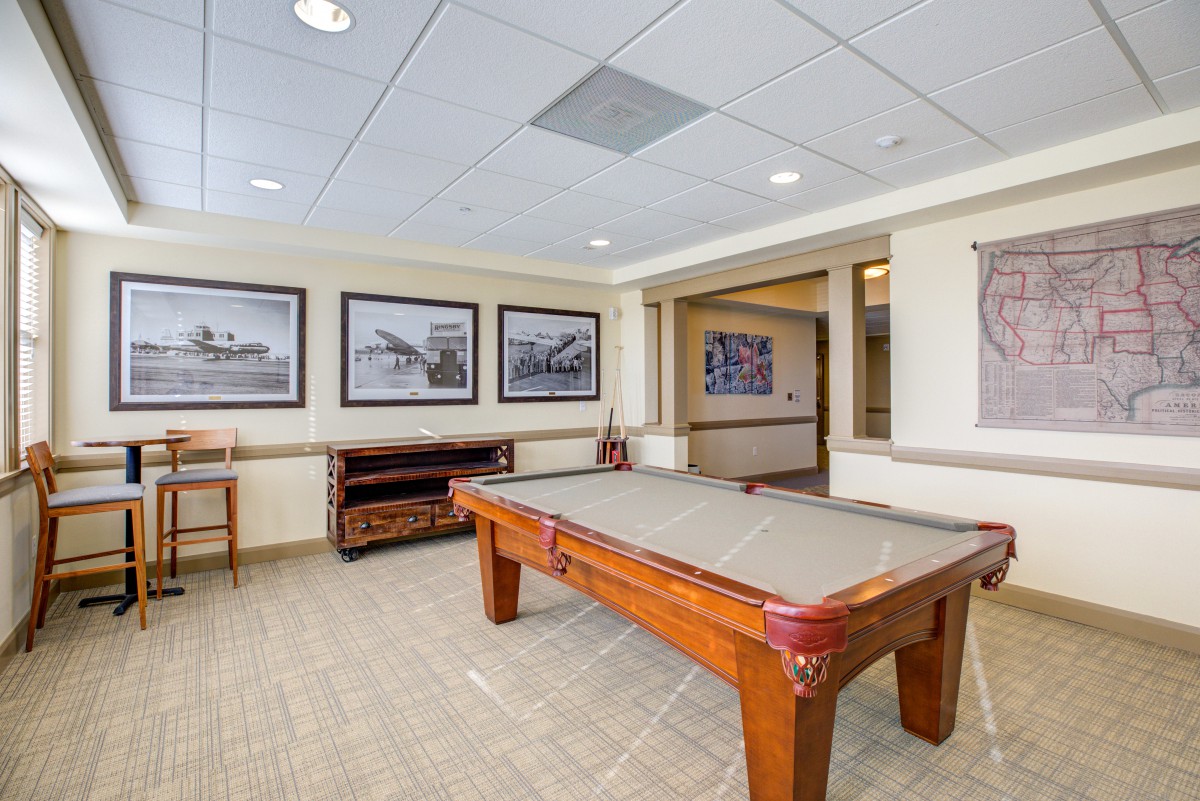 A well-lit billiards room featuring a pool table and framed photographs on the walls.