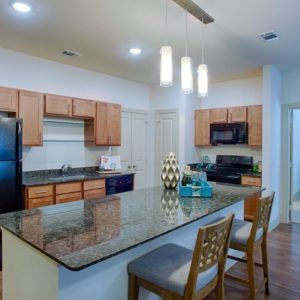 A modern kitchen with a central island, featuring wood cabinets and contemporary lighting.