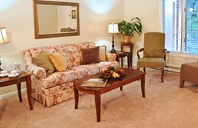 A cozy living room with a floral sofa, a wooden coffee table, and a decorative lamp.