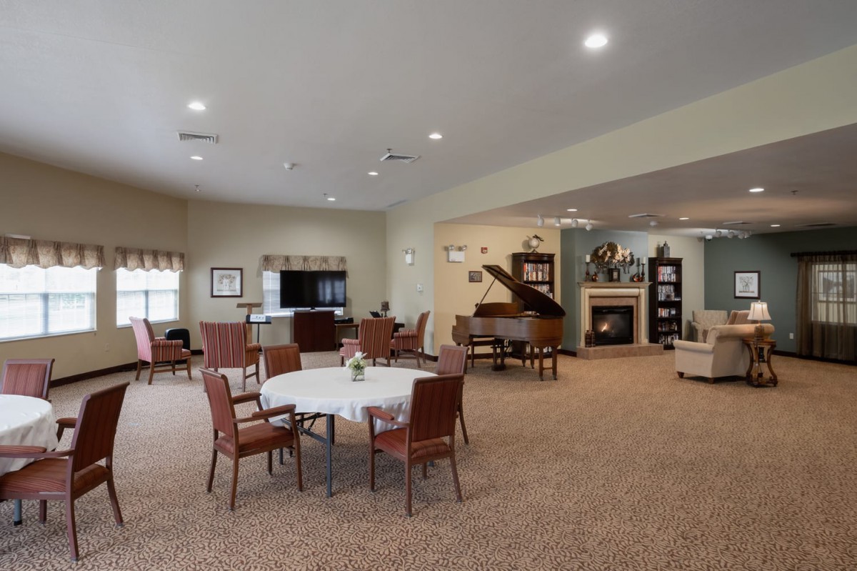 A cozy interior room featuring tables and chairs, a fireplace, and a piano.