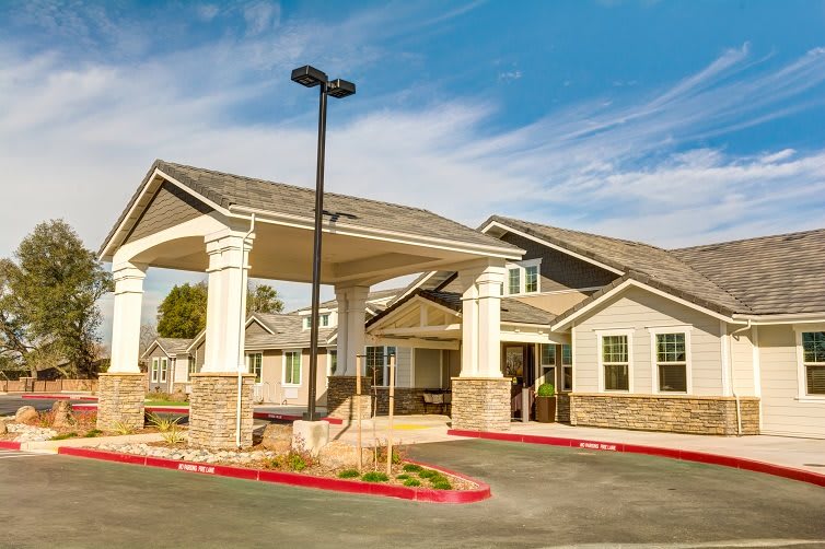A residential building with a covered entrance and a driveway under a blue sky.